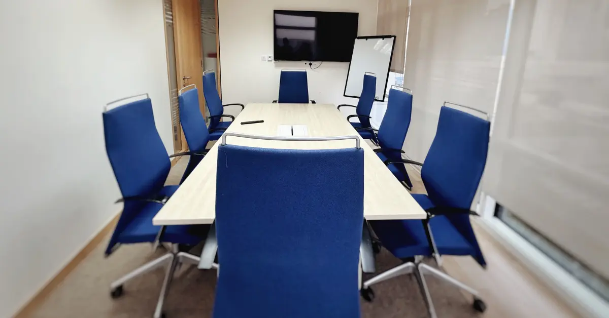 Professional conference room with blue chairs and a presentation screen, ideal for client meetings in Dubai.